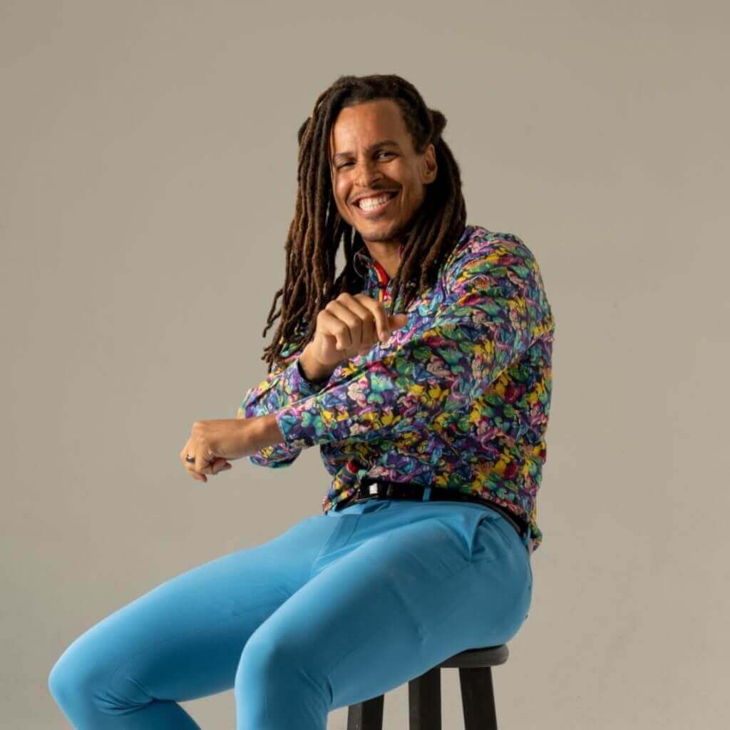 Coach seated on a stool in a colorful patterned shirt