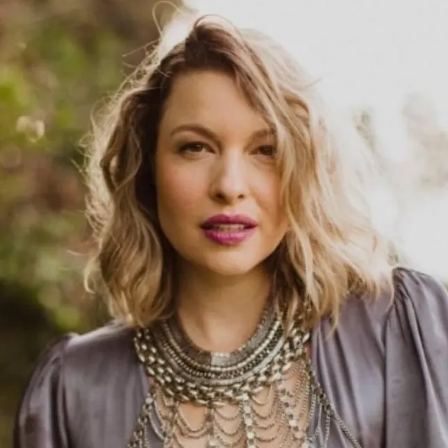 Woman with wavy hair and a statement necklace, coach portrait