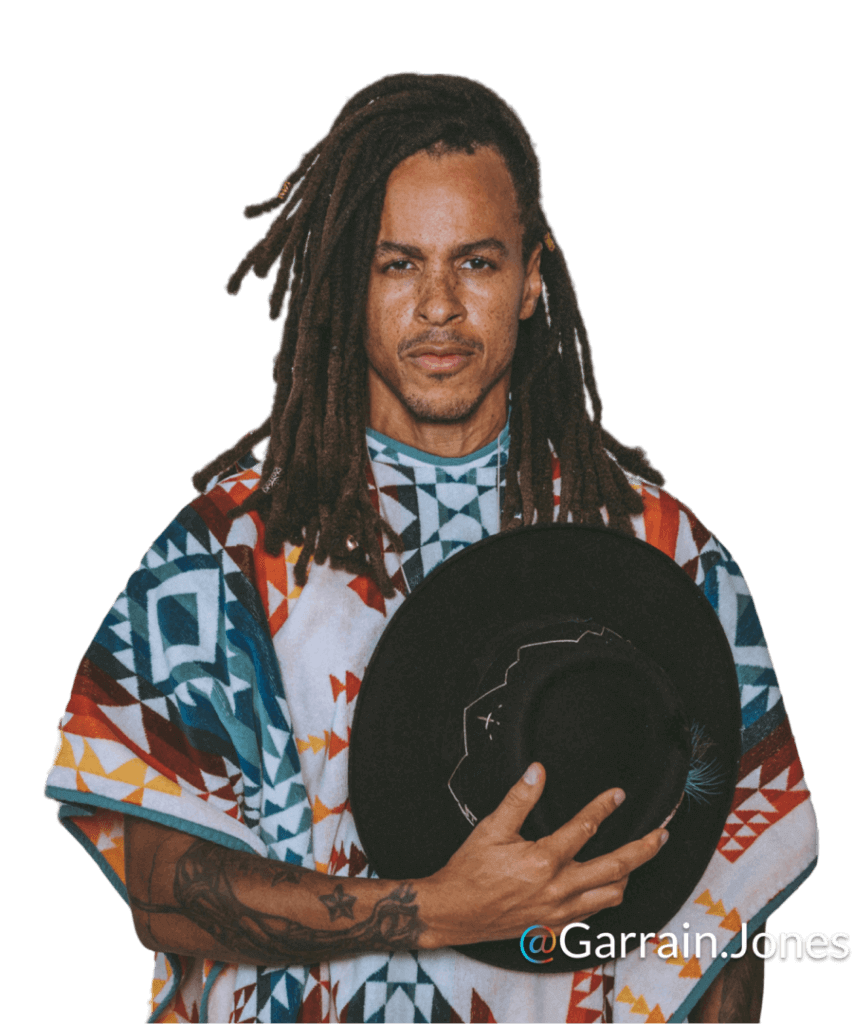 Man with long locs holding a black hat, portrait